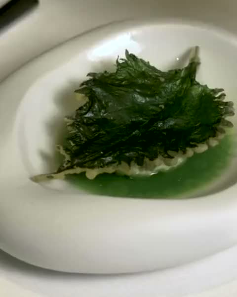 Green sauce poured over a leaf, in motion